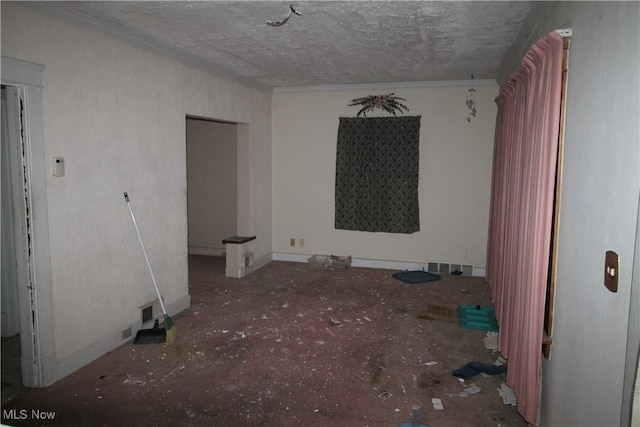 spare room featuring ornamental molding, a textured ceiling, and visible vents
