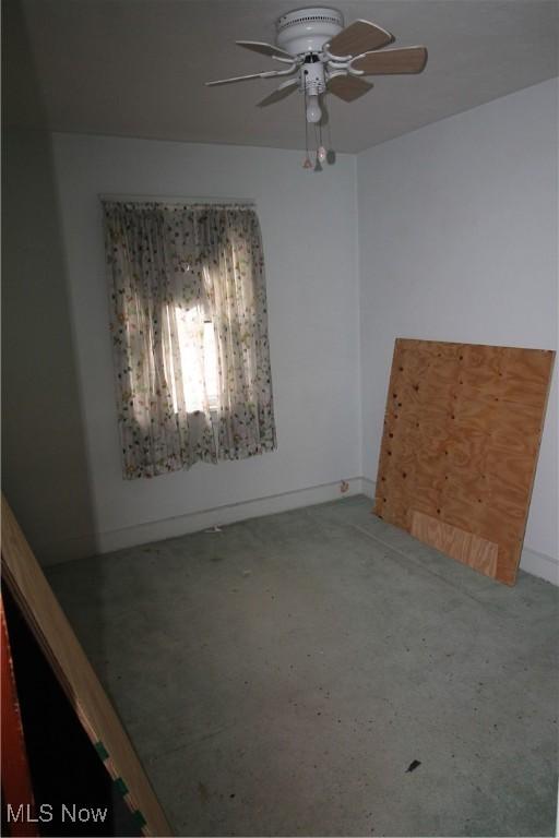 carpeted spare room featuring baseboards and ceiling fan