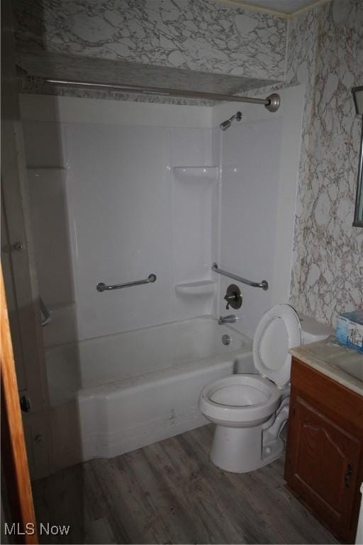 full bathroom with wood finished floors, vanity, toilet, shower / bathtub combination, and wallpapered walls