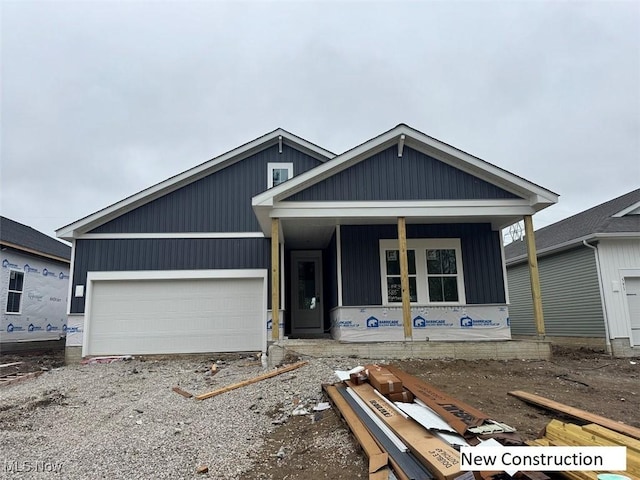 unfinished property featuring a garage, a porch, and gravel driveway
