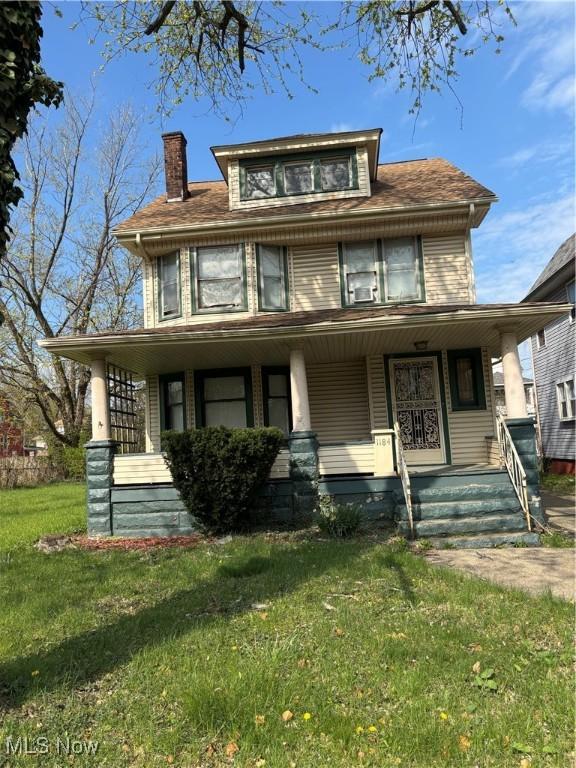 view of front facade with covered porch, a chimney, and a front lawn