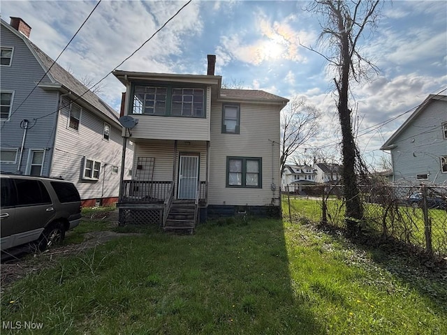 rear view of property with covered porch, a lawn, and fence