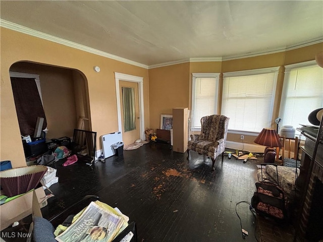 sitting room with arched walkways, ornamental molding, and wood-type flooring