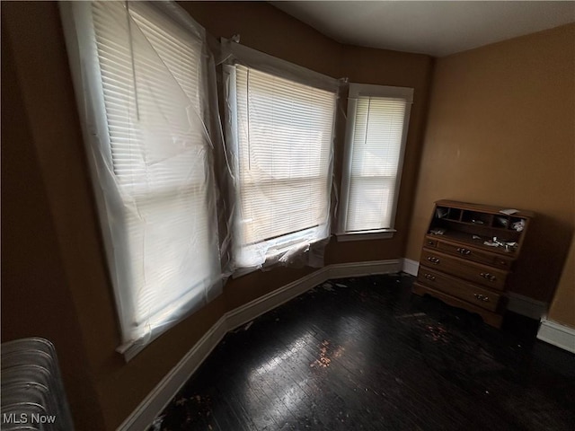 spare room featuring baseboards and wood finished floors