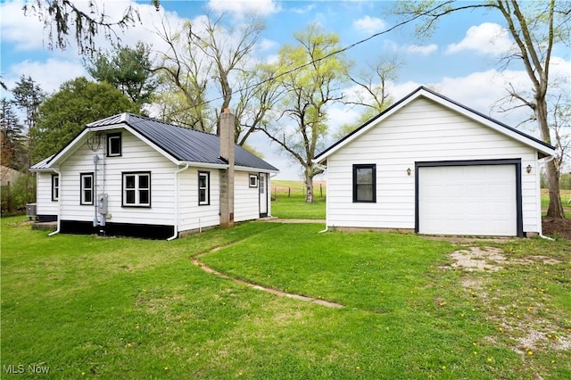 back of house featuring a lawn, a chimney, metal roof, and a garage