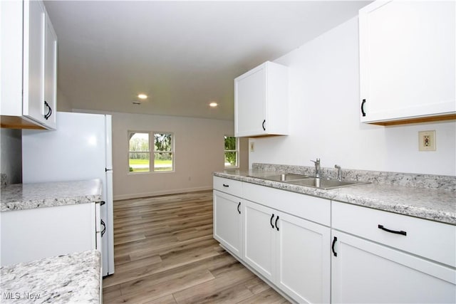 kitchen featuring a sink, white cabinets, and light wood-style floors