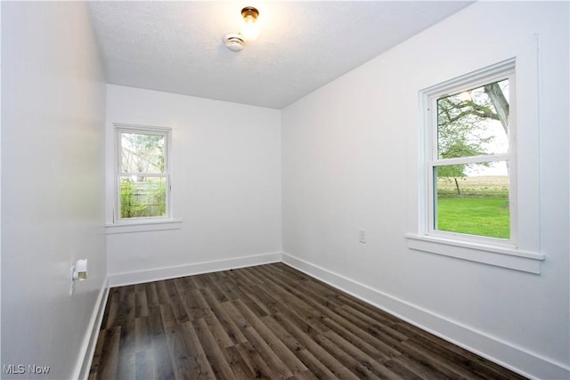 spare room featuring baseboards and dark wood finished floors