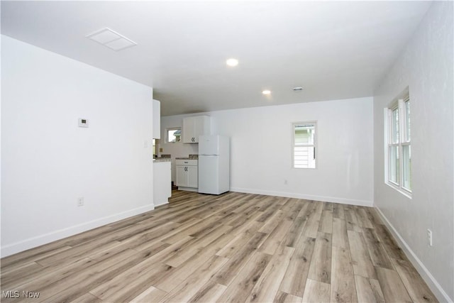 unfurnished living room with baseboards, recessed lighting, and light wood-style flooring