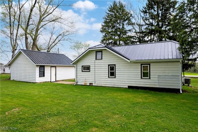 back of house with a lawn, central AC unit, and metal roof