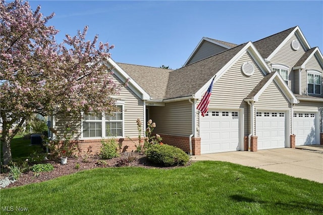 view of front of house with a shingled roof, brick siding, a garage, a front yard, and concrete driveway