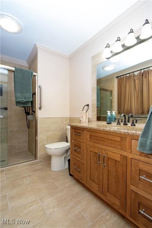 full bath featuring crown molding, tile patterned flooring, toilet, tile walls, and a shower stall