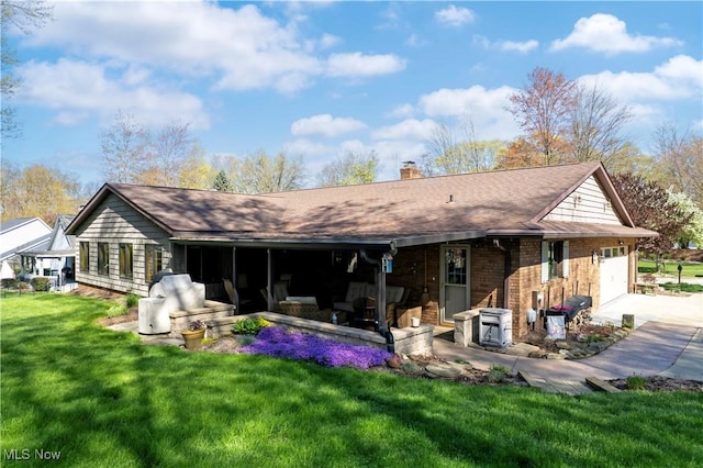 rear view of property with a garage, a chimney, brick siding, concrete driveway, and a yard