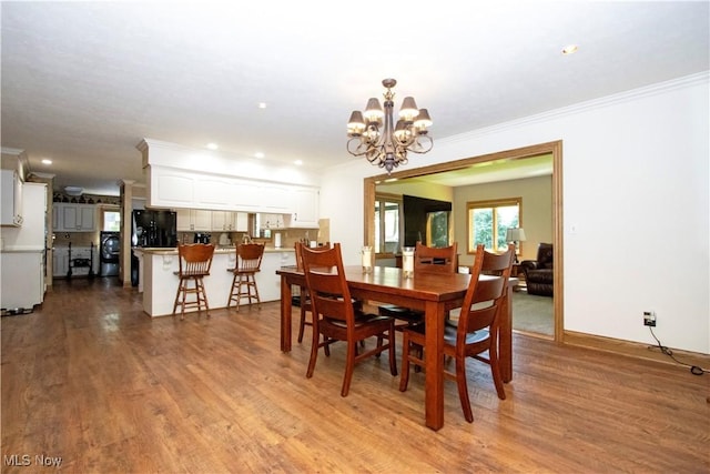 dining room with an inviting chandelier, crown molding, recessed lighting, and wood finished floors
