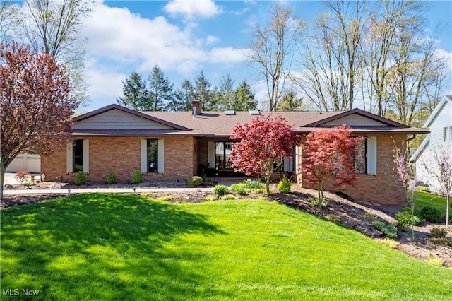 ranch-style house featuring brick siding, a chimney, and a front lawn