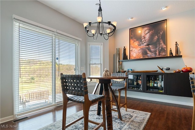 dining room with an inviting chandelier, baseboards, wood finished floors, and visible vents
