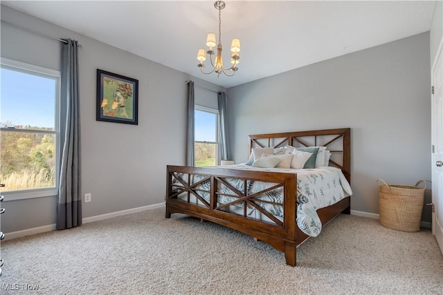carpeted bedroom featuring baseboards and a chandelier