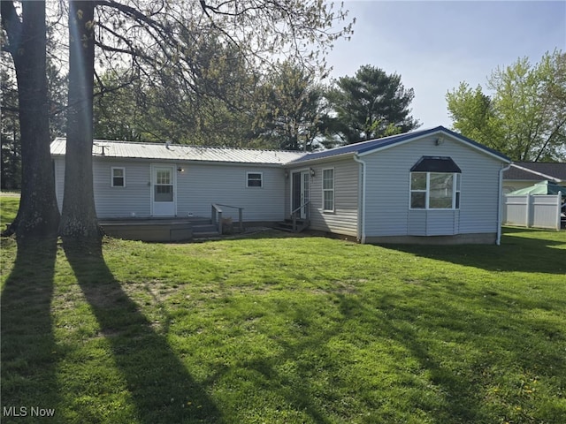 rear view of house with a lawn, a wooden deck, metal roof, and entry steps