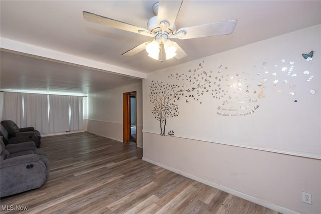 unfurnished living room featuring a ceiling fan, baseboards, and wood finished floors