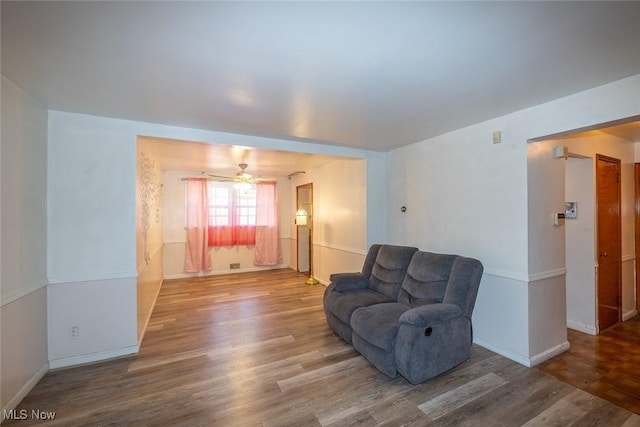 sitting room with baseboards, a ceiling fan, and wood finished floors