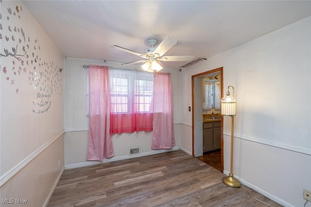 unfurnished room with visible vents, a ceiling fan, baseboards, and wood finished floors