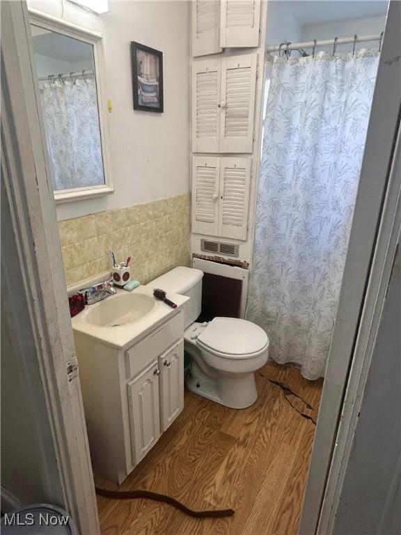 bathroom with vanity, toilet, a shower with shower curtain, tile walls, and wood finished floors