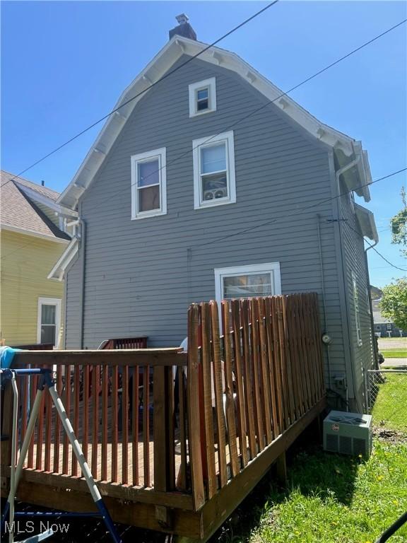 rear view of house with a wooden deck, a chimney, and central AC unit