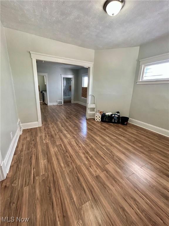 unfurnished room featuring baseboards, a textured ceiling, and wood finished floors