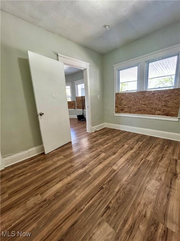 unfurnished room featuring baseboards, a textured ceiling, and wood finished floors