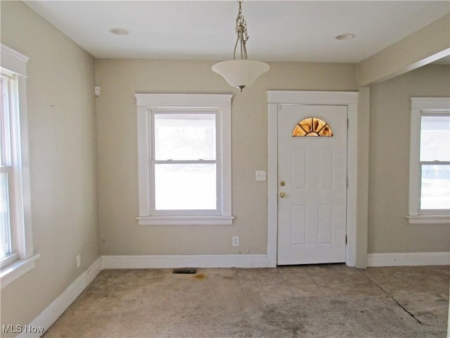 entrance foyer with visible vents, a wealth of natural light, and light carpet