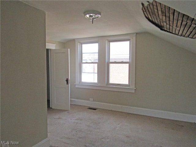 additional living space with carpet flooring, baseboards, visible vents, and lofted ceiling