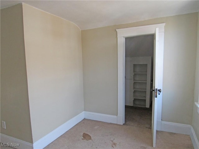 unfurnished room with baseboards and light carpet