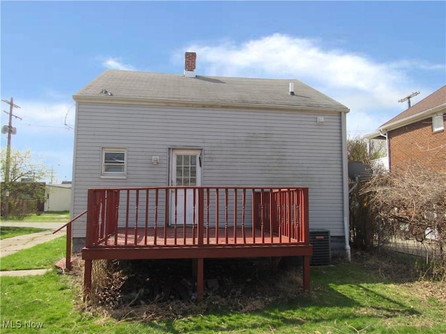 rear view of house featuring a yard, a deck, cooling unit, and a chimney