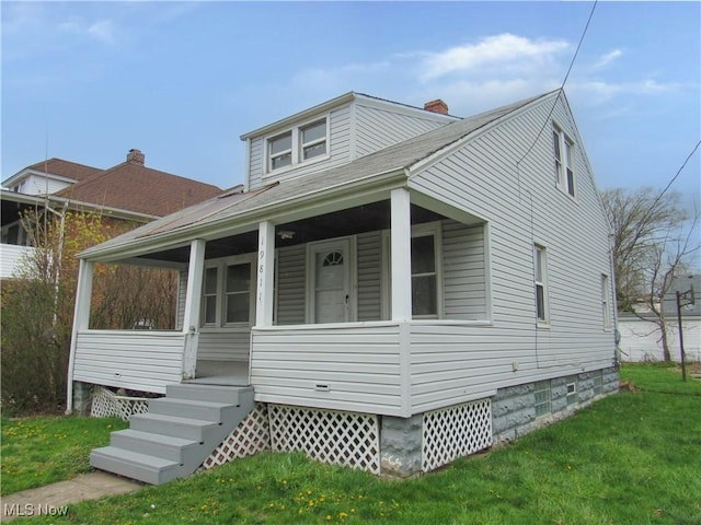 bungalow-style home with a porch, a chimney, a shingled roof, and a front lawn