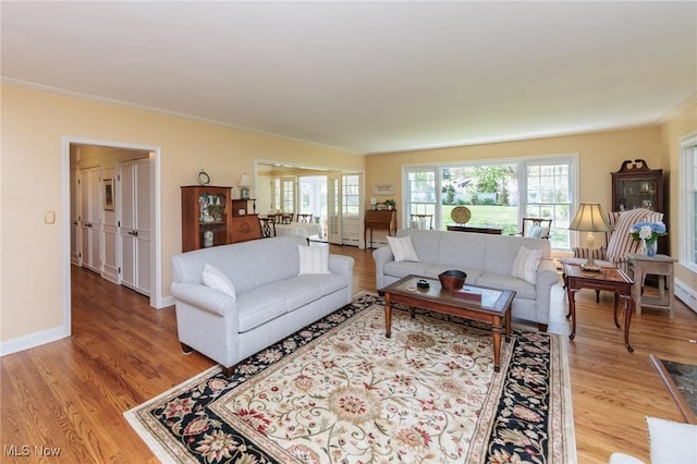 living area with crown molding, light wood-style flooring, and baseboards