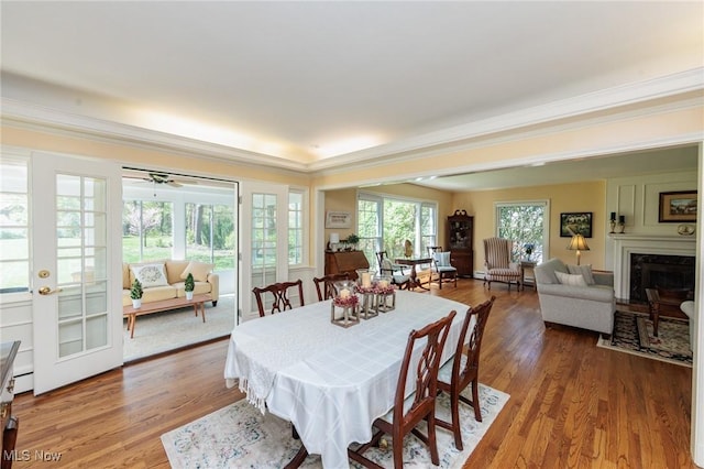 dining room featuring crown molding, a large fireplace, and wood finished floors