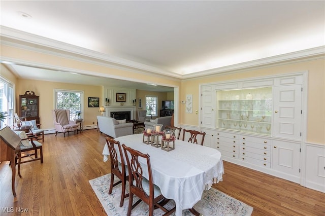 dining area with crown molding, a large fireplace, and wood finished floors
