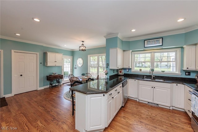 kitchen with white cabinets, a sink, a kitchen breakfast bar, stainless steel appliances, and a peninsula