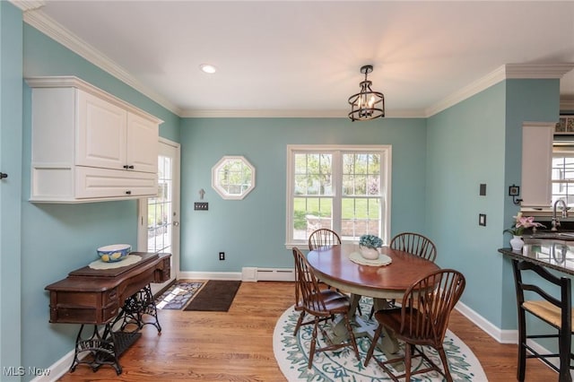 dining space featuring wood finished floors, ornamental molding, baseboards, and a baseboard heating unit