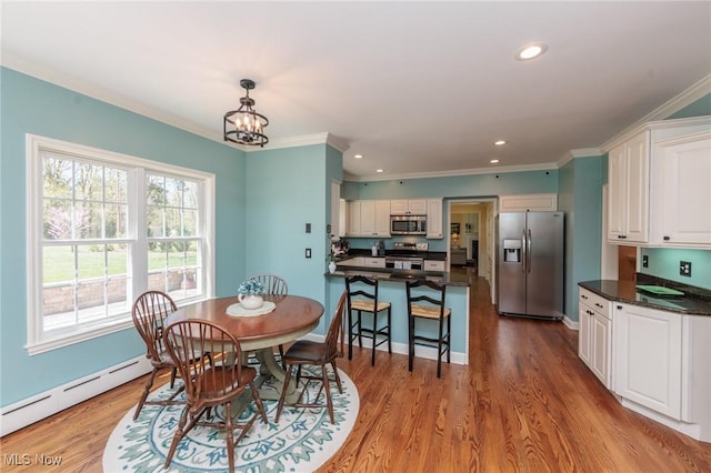 dining room with crown molding, a baseboard heating unit, a chandelier, and wood finished floors