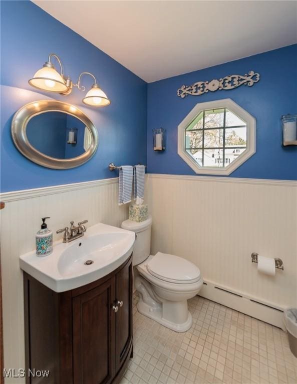 bathroom featuring vanity, toilet, baseboard heating, and a wainscoted wall
