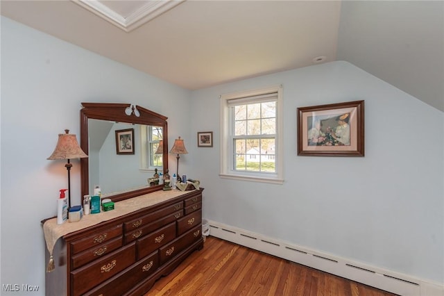 bedroom featuring wood finished floors, a baseboard heating unit, and vaulted ceiling