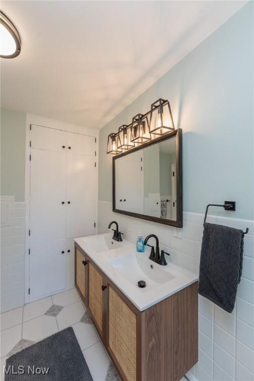 full bath featuring a sink, tile walls, wainscoting, and double vanity