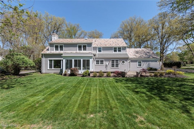 rear view of property featuring a lawn and a chimney