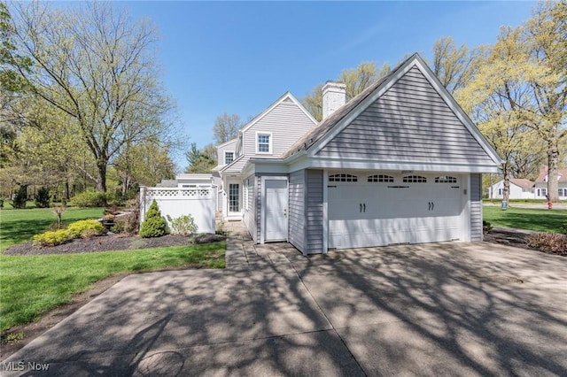 view of front of home featuring a garage, a chimney, driveway, and a front lawn