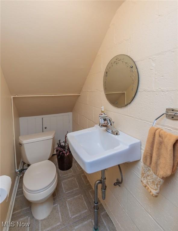 half bathroom featuring toilet and lofted ceiling