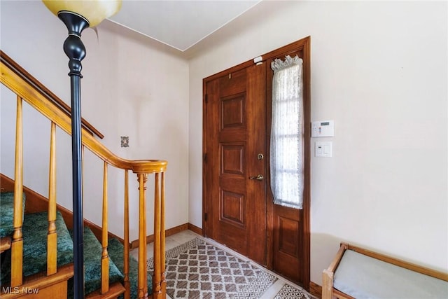 foyer featuring stairs and baseboards