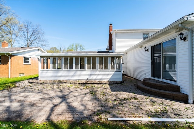 rear view of house featuring a chimney and a sunroom