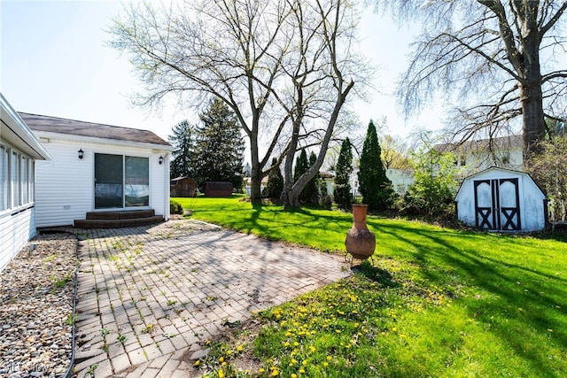 view of yard featuring a storage unit, entry steps, an outbuilding, and a patio