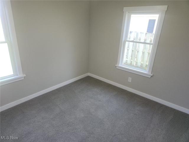 empty room with baseboards and dark carpet