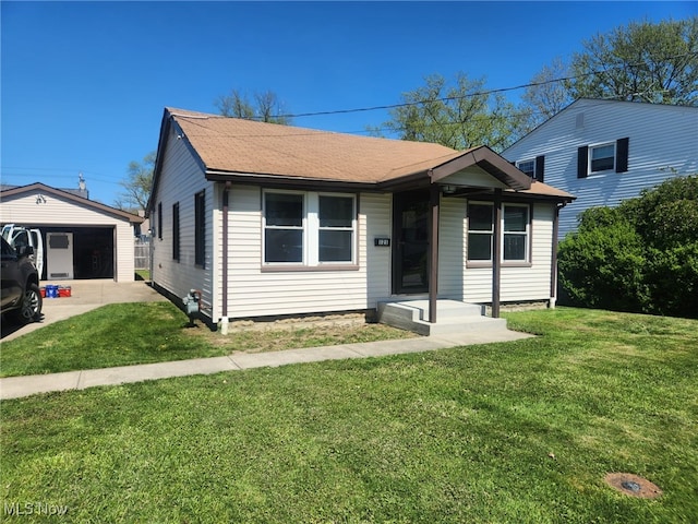 bungalow with a garage, an outbuilding, a shingled roof, and a front yard